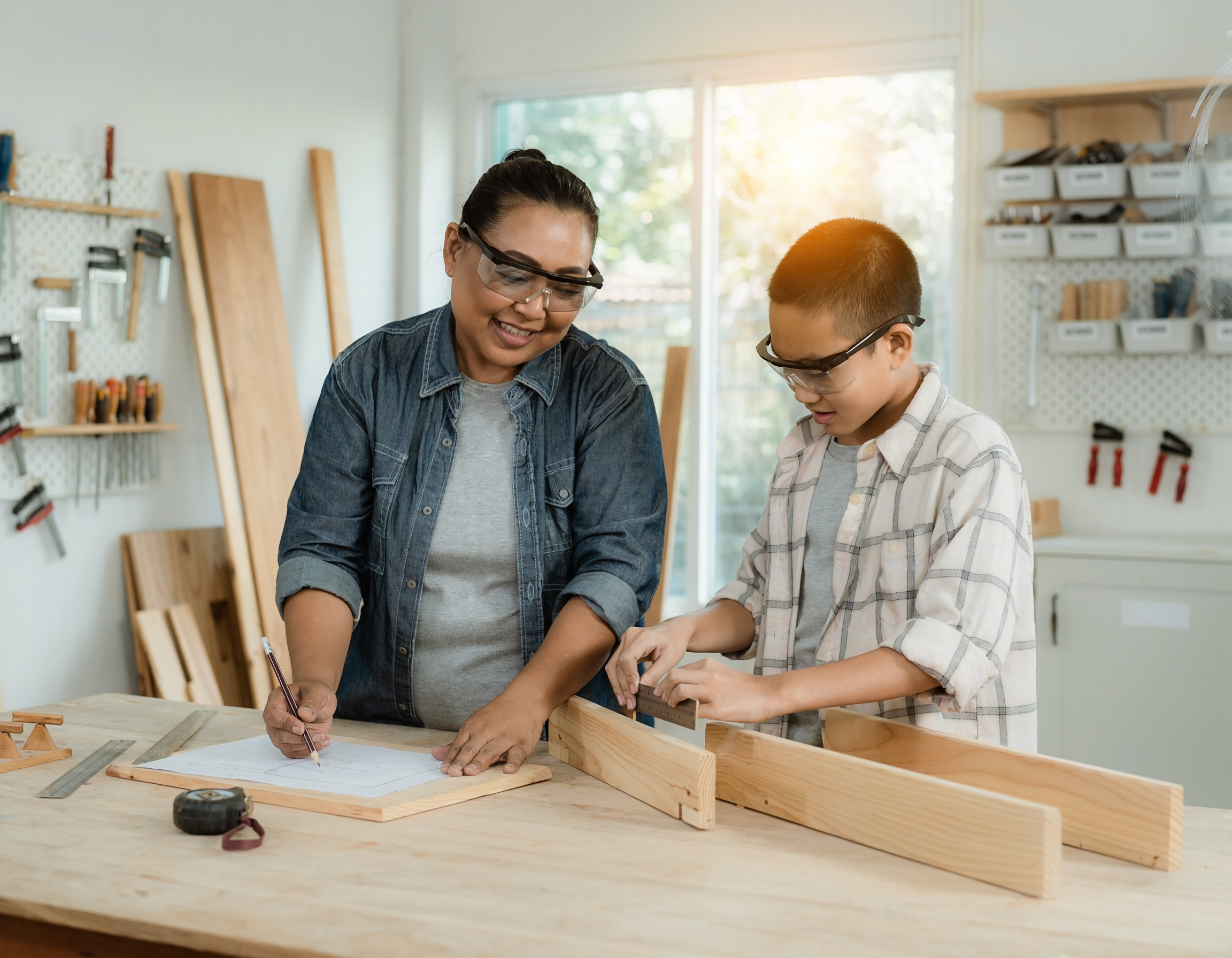 Adult mentor and young maker planning a woodworking project together at a bench